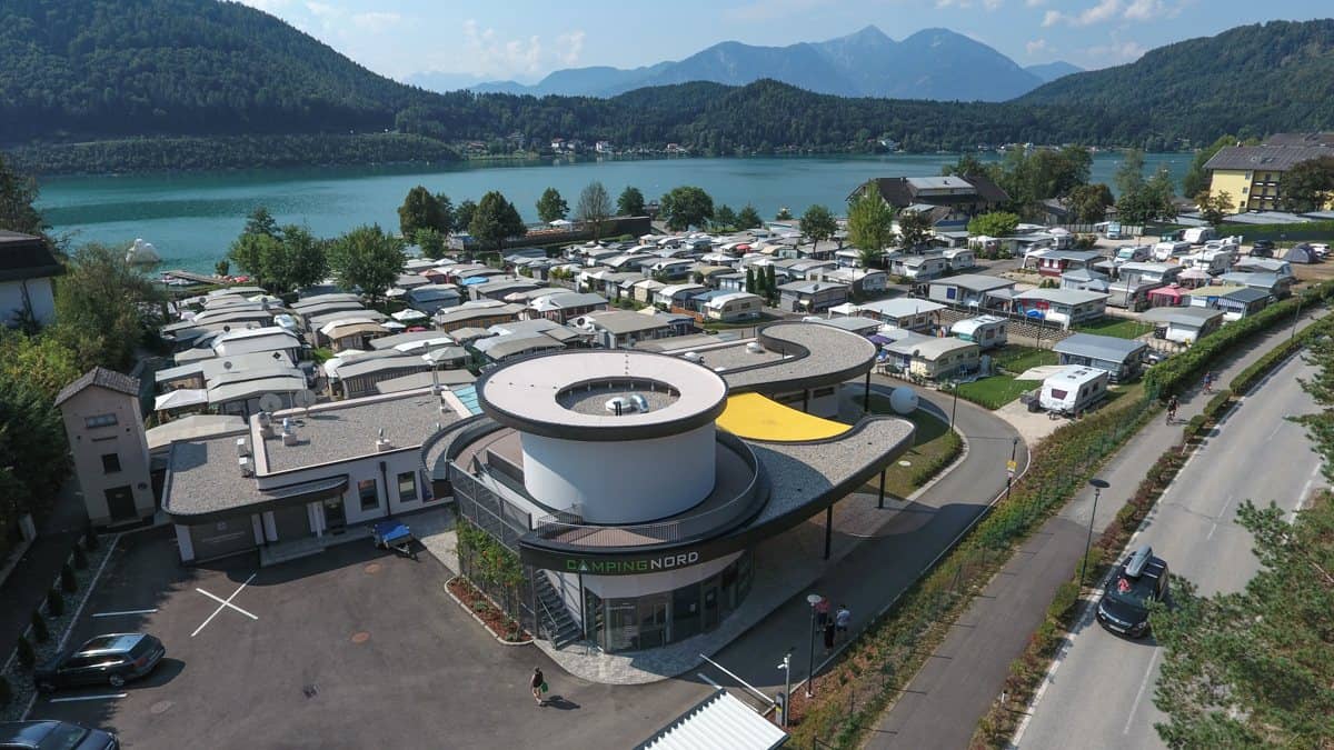 Das runde Rezeptionsgebäude von Camping Nord, dahinter Stellplätze und See