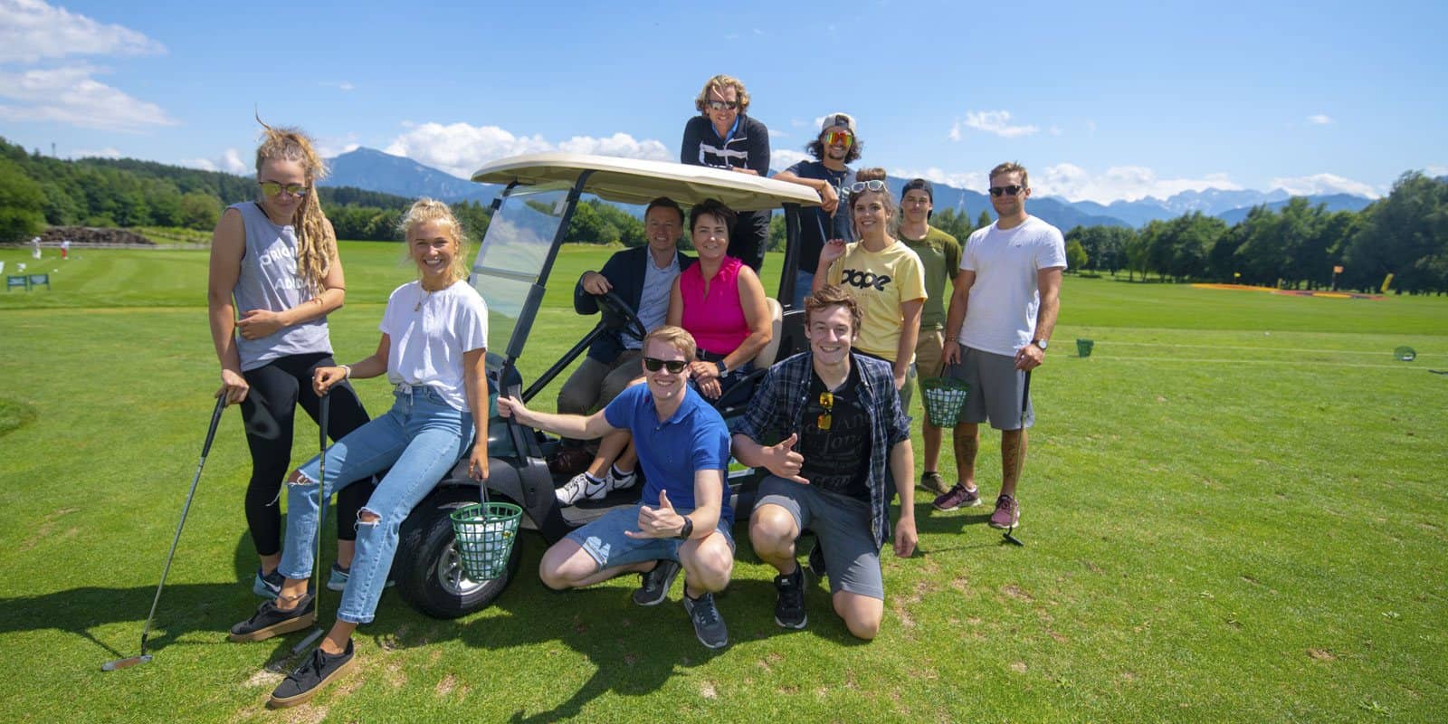 Gruppe junger Leute mit Golfcart auf dem Golfplatz