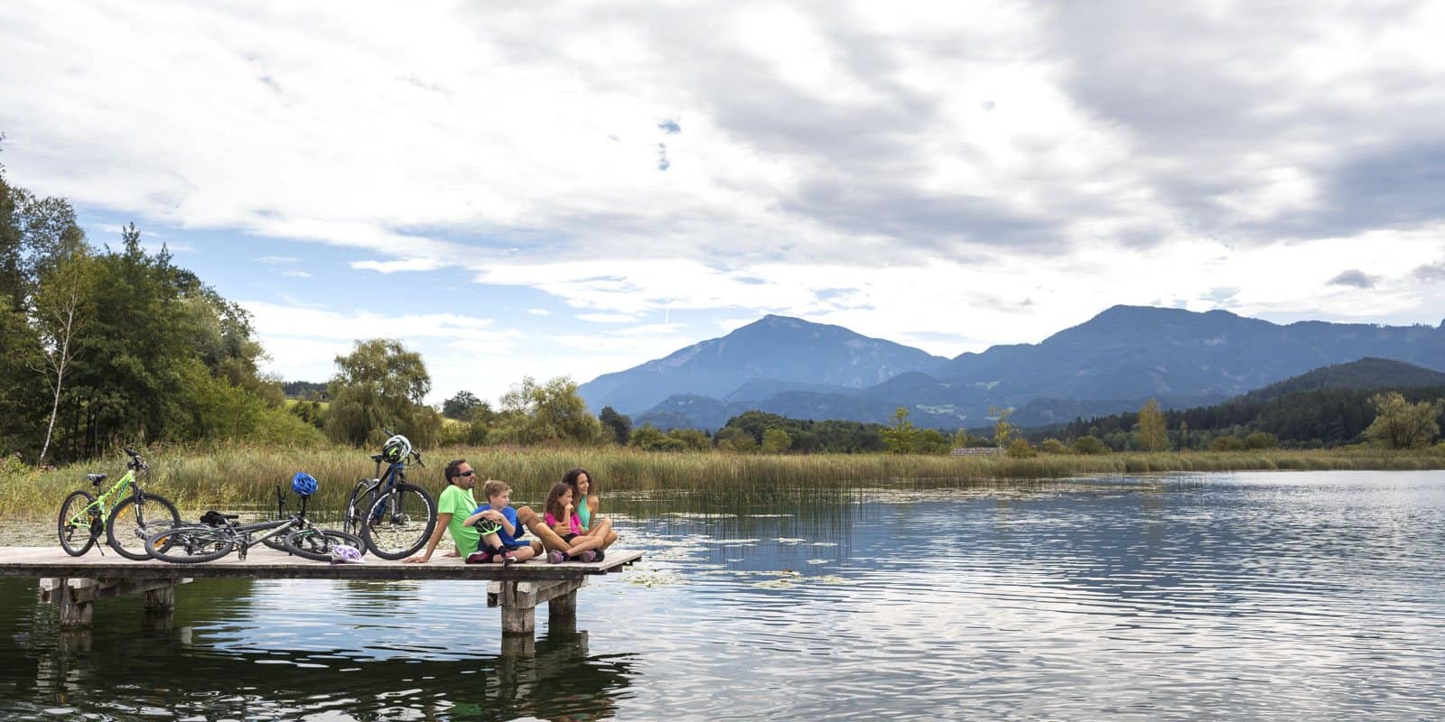 Radfahrer machen Pause auf einem Steg am See