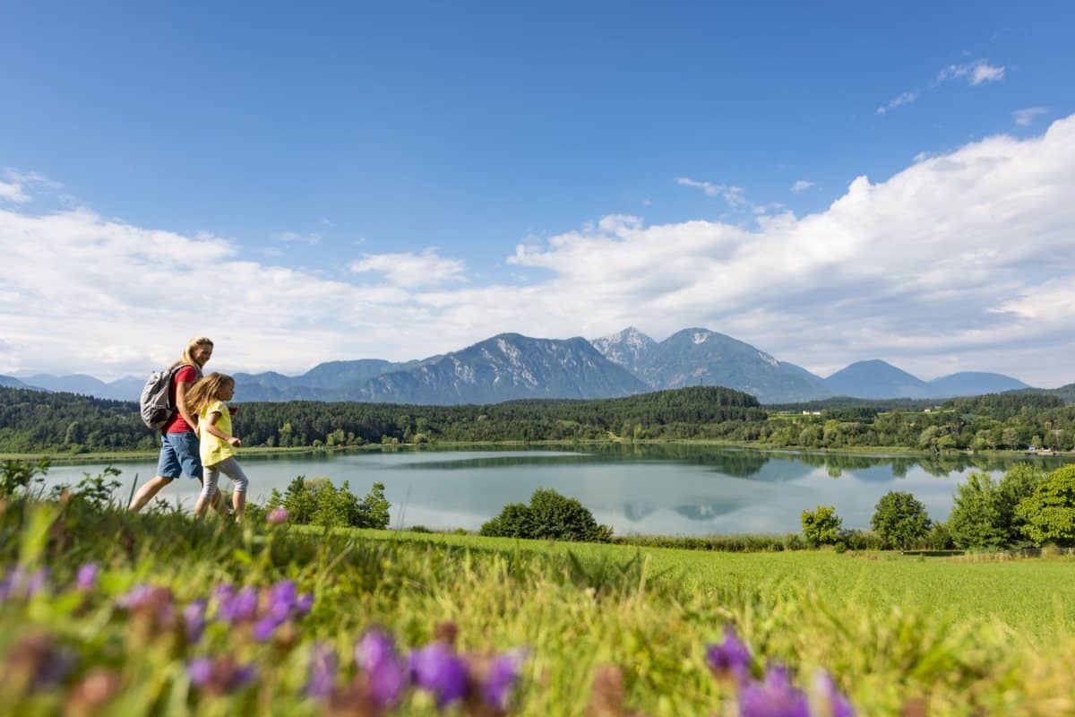Wanderer auf einer Blumenwiese über dem Klopeiner See