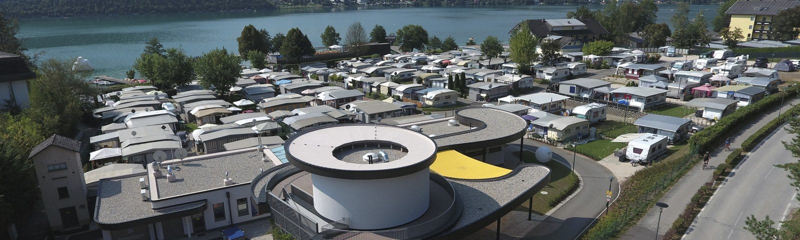 Stellplätze und Rundbau mit Blick auf den See
