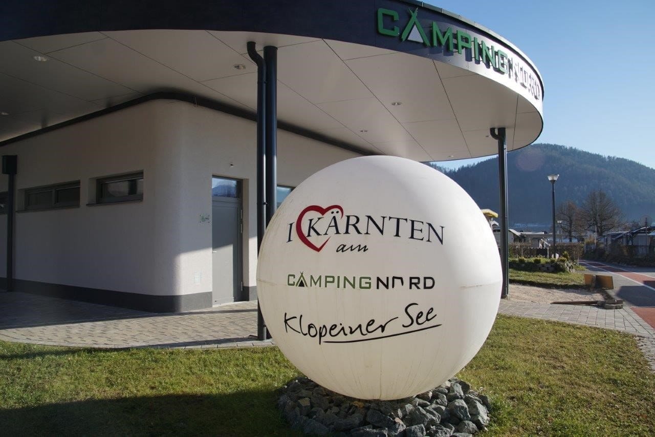 Weiße Kugel mit Camping-Nord-Logo vor dem überdachten Eingang