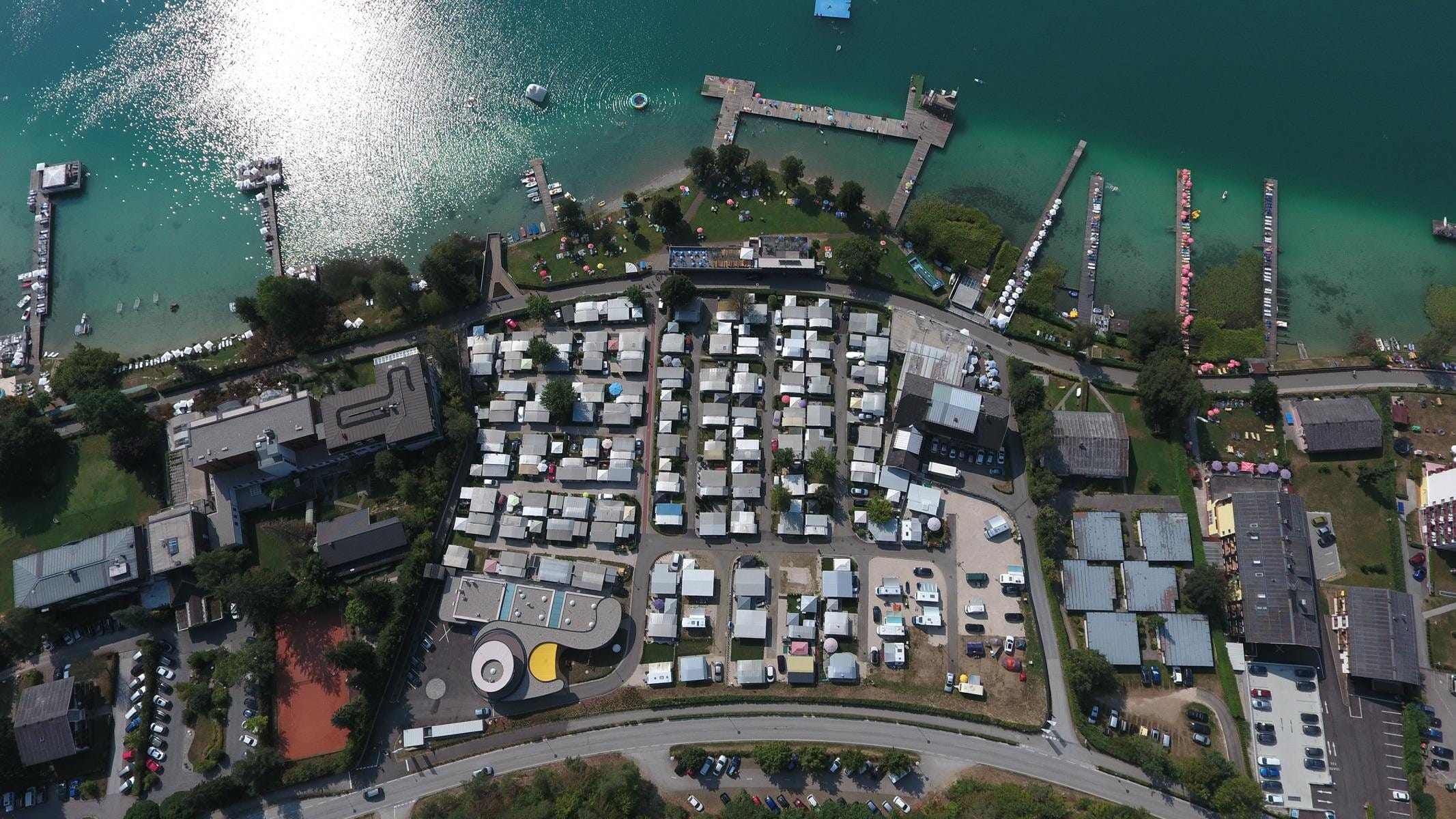 Senkrechte Luftaufnahme: Stellplätze, Sanitärgebäude und Seeufer von Camping Nord