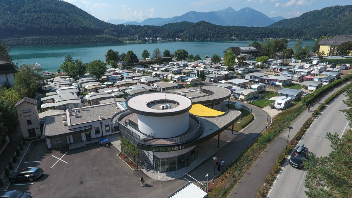 Das runde Rezeptionsgebäude von Camping Nord, dahinter Stellplätze und See